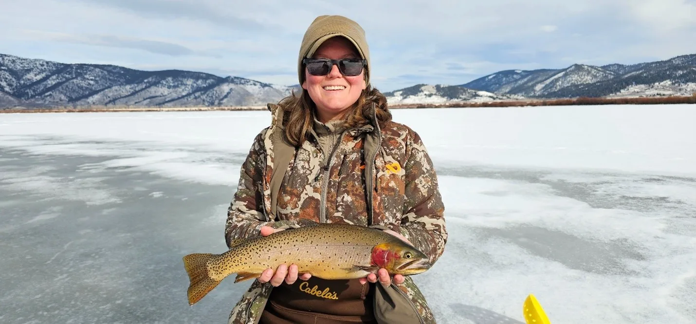 Full Camo Ice Angler holding a large trout